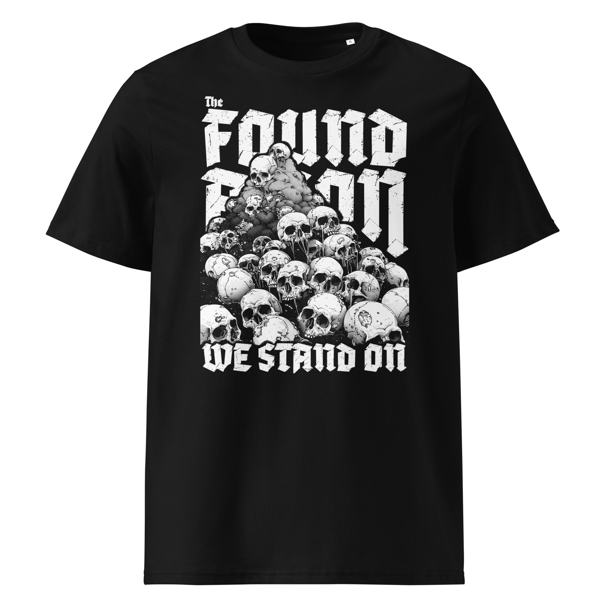 Vorderansicht eines schwarzen T-Shirts mit dem Motiv 'The Foundation We Stand On': Ein großer Haufen aus realistisch gezeichneten Totenschädeln bildet die Basis für einen massiven, weißen Schriftzug in einer modernen Gothic-Schriftart.