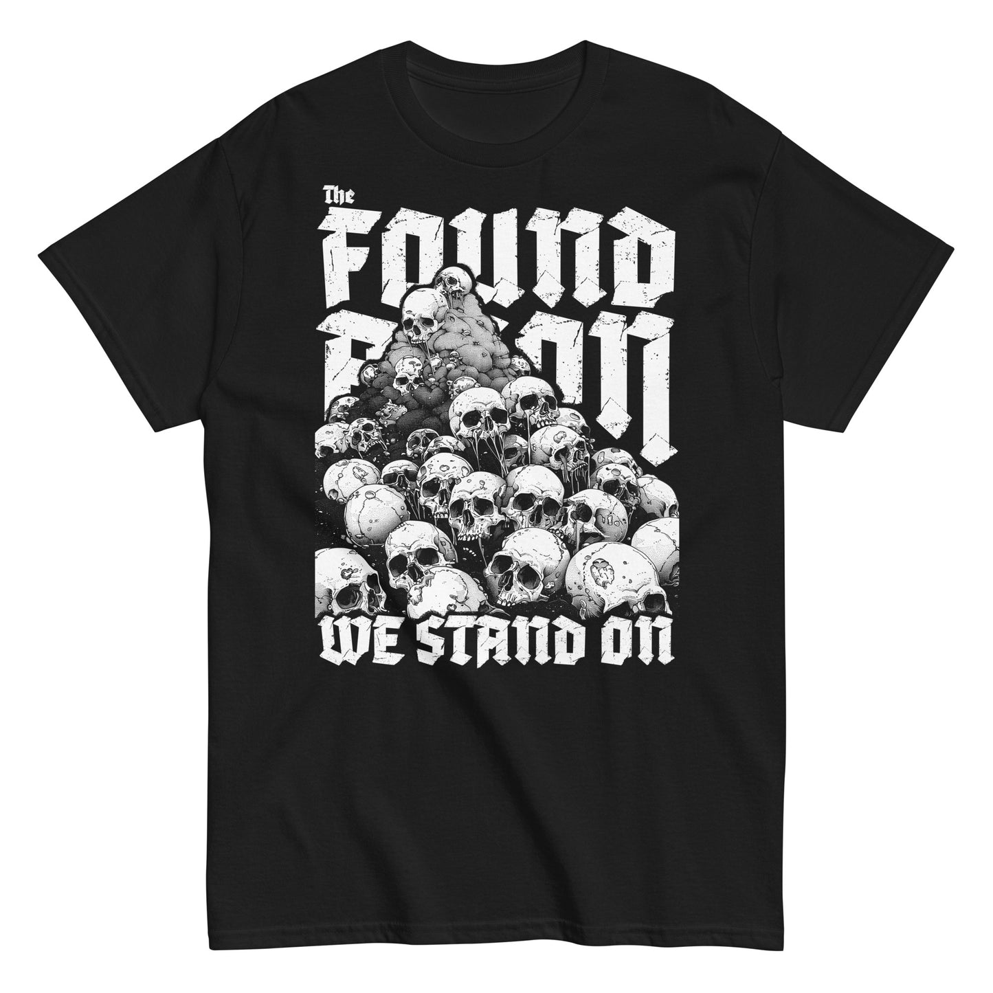 T-Shirt mit einem Berg aus Totenköpfen und dem Slogan 'The foundation we stand on'. Das Design ist Weiß auf schwarzem/dunkeln Stoff und thematisiert die brutalen Hintergründe von Landbesitz und Eroberung.